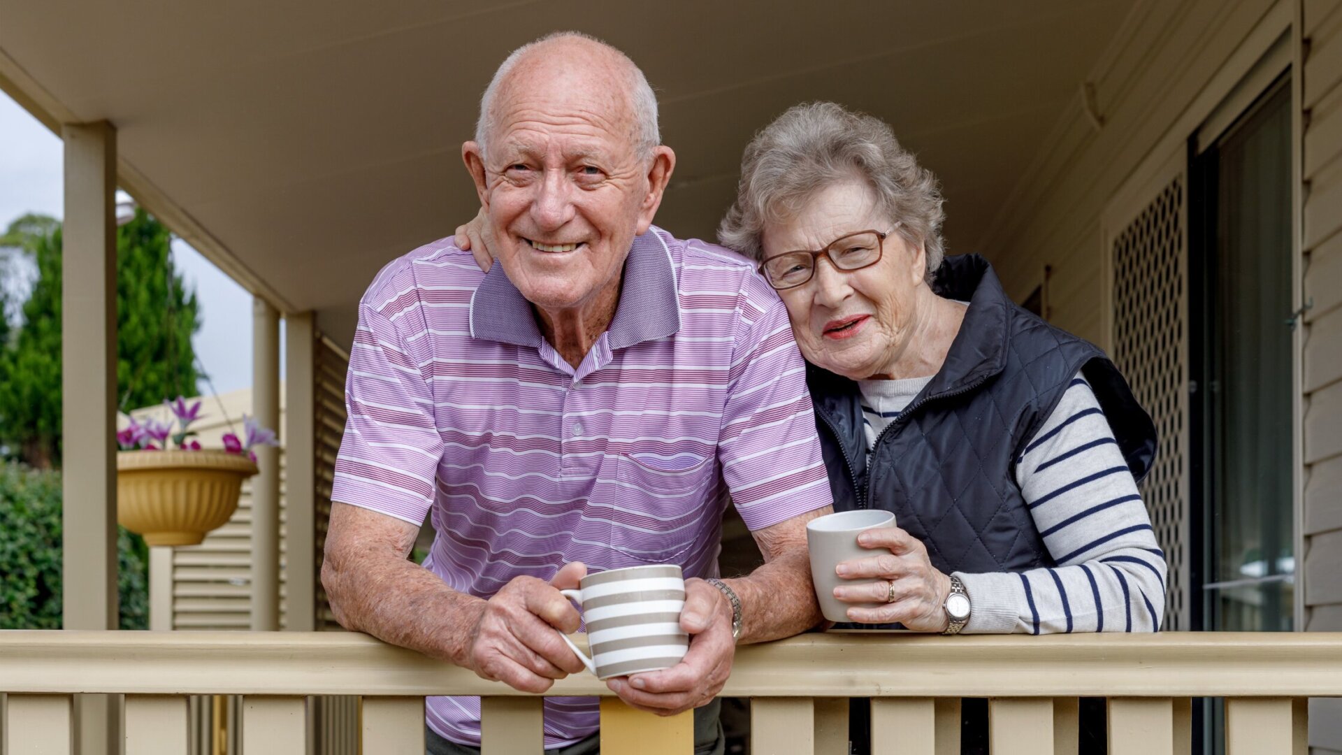 Senior man and woman standing on their porch of their Garden Home at Traditions at Reagan Park
