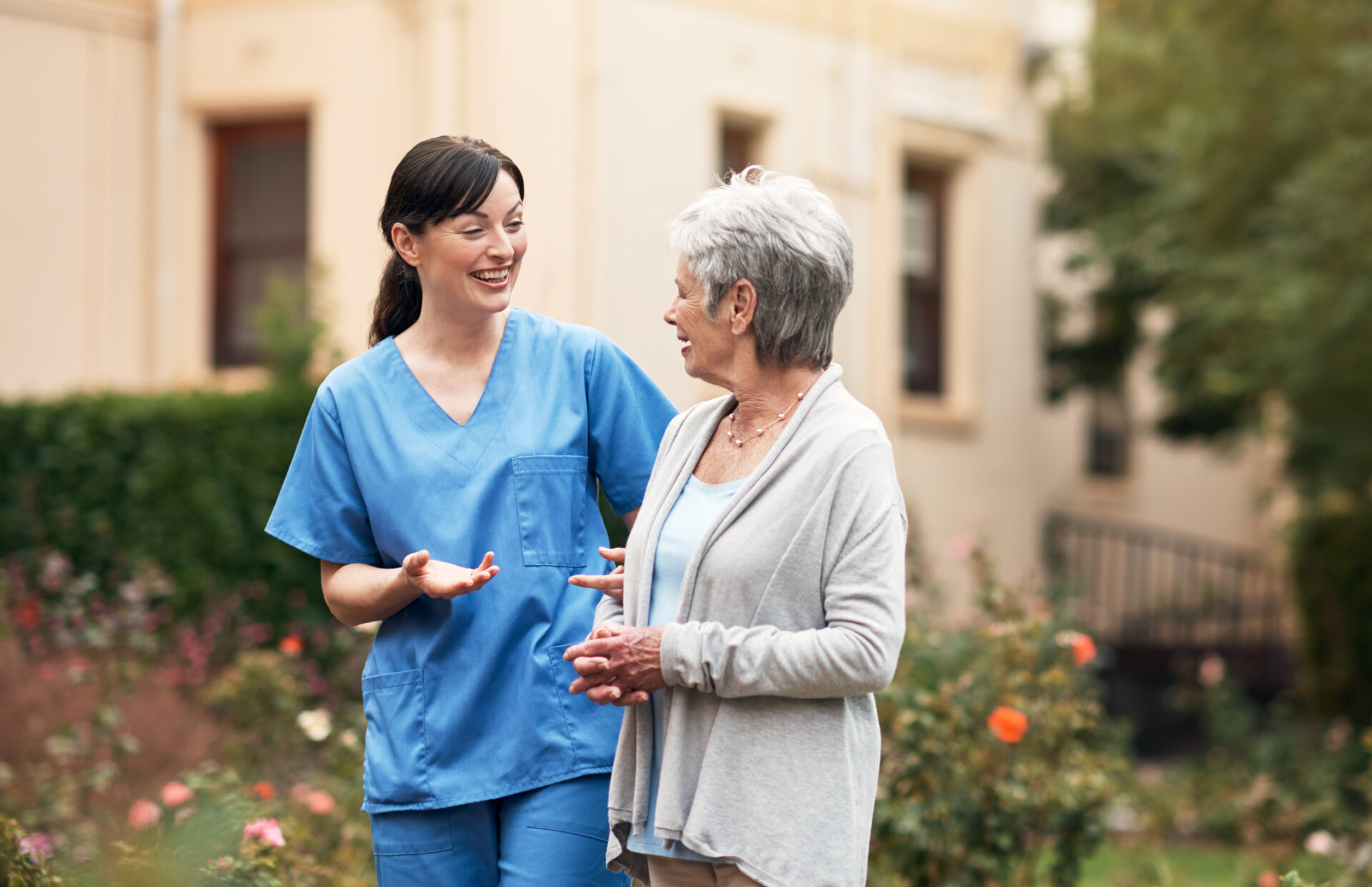Senior memory care resident walking outdoors with her caregiver at Traditions at Reagan Park