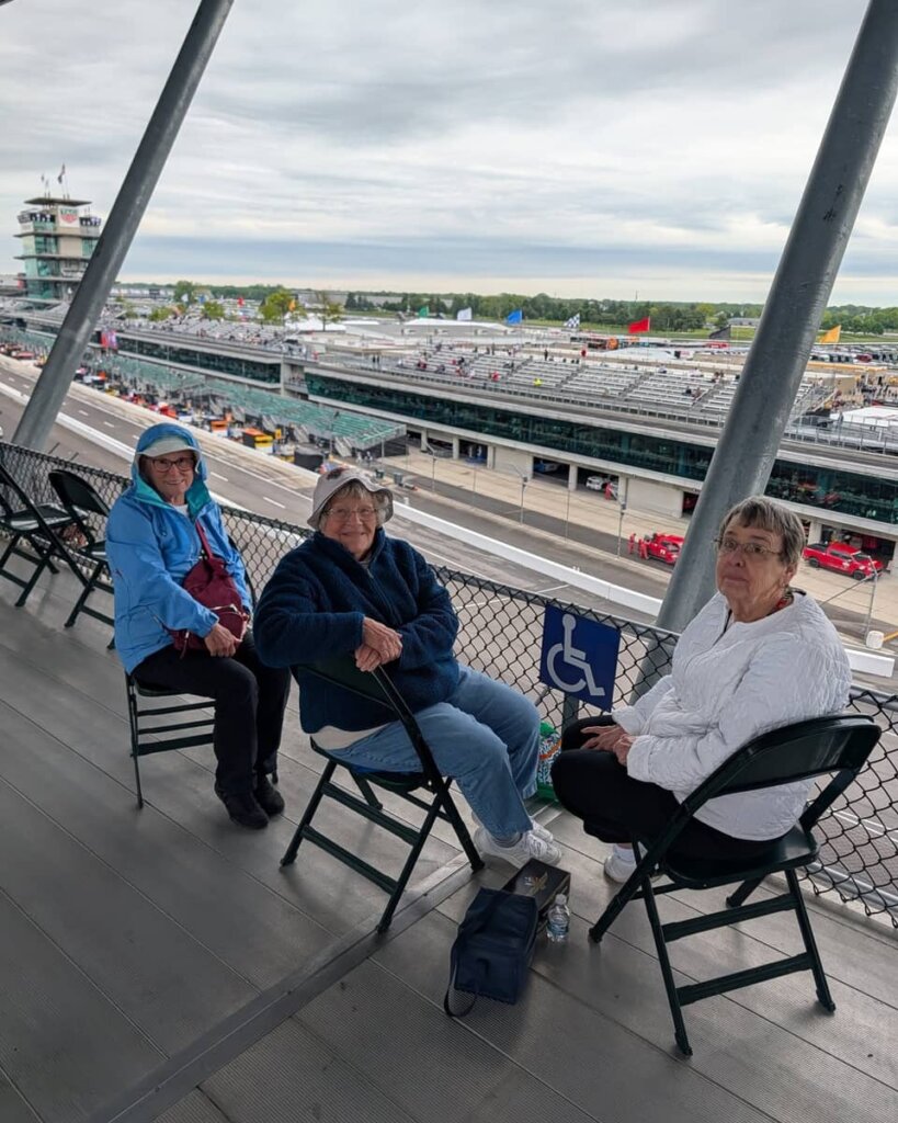 Three residents enjoy seats in the grandstand overlooking the track during an Indianapolis 500 outing organized by Traditions at Reagan Park.